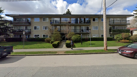 A person is walking on a sidewalk in front of a building.