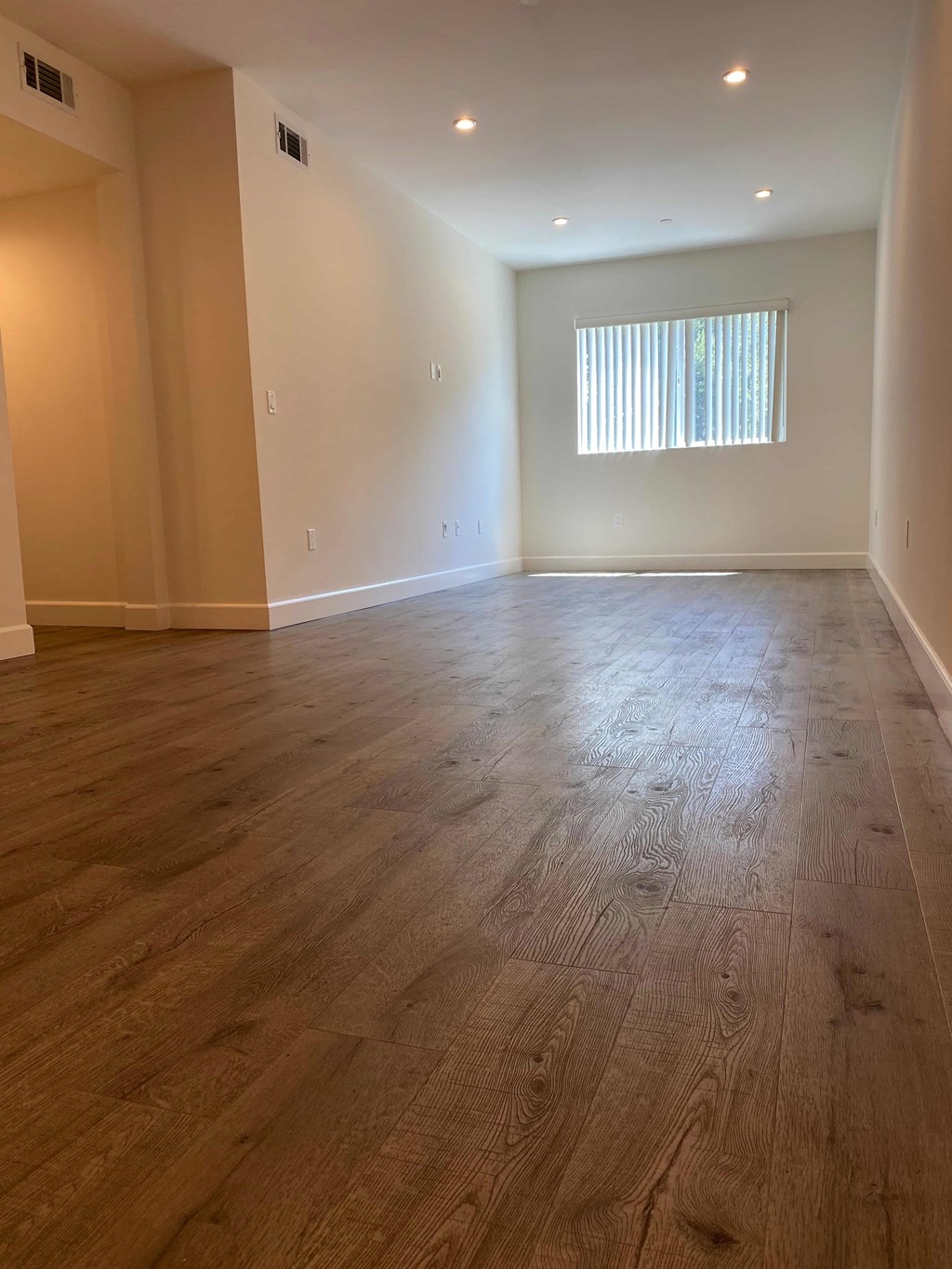 A room with wooden flooring and a window with blinds.