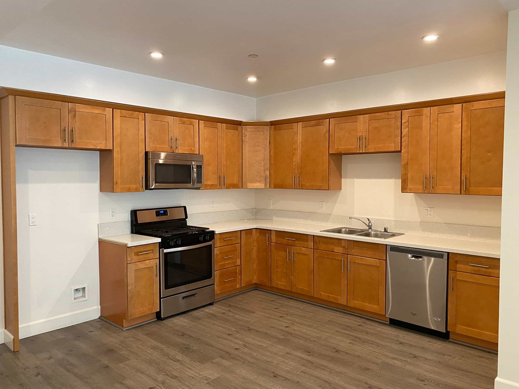 A kitchen with wooden cabinets and a stainless steel dishwasher.