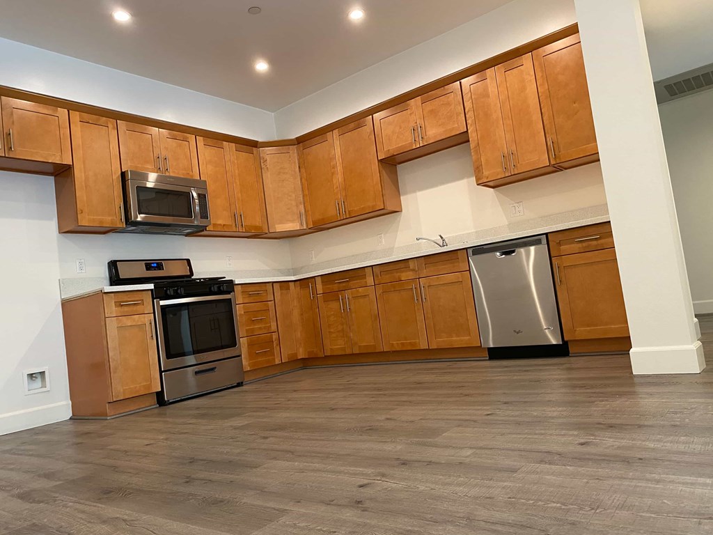 A kitchen with wooden cabinets and a stainless steel dishwasher.