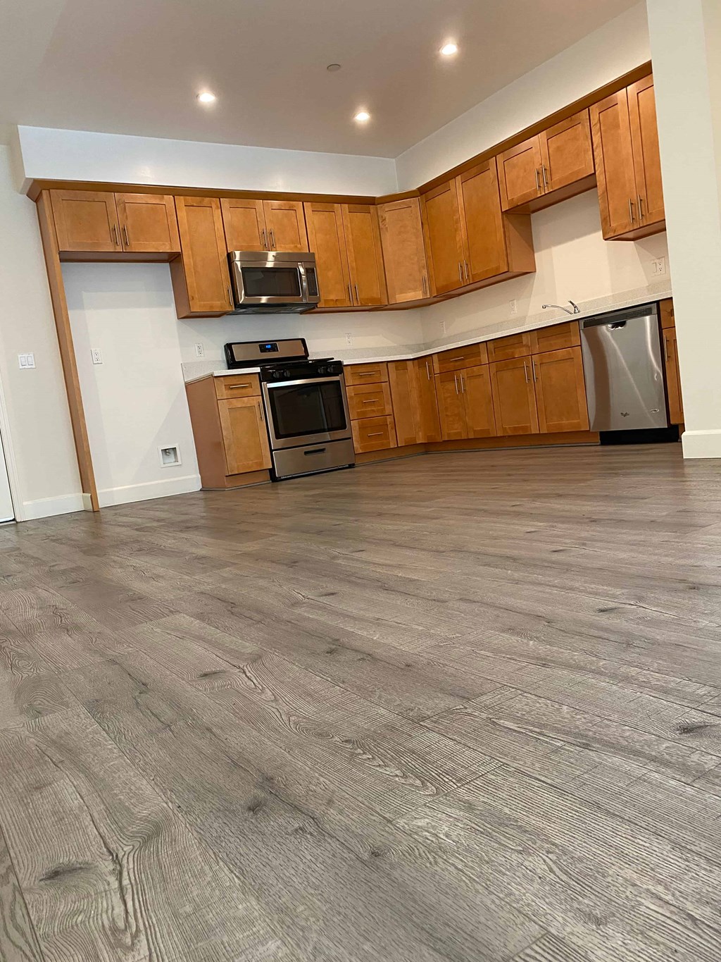 A kitchen with wooden cabinets and a grey floor.