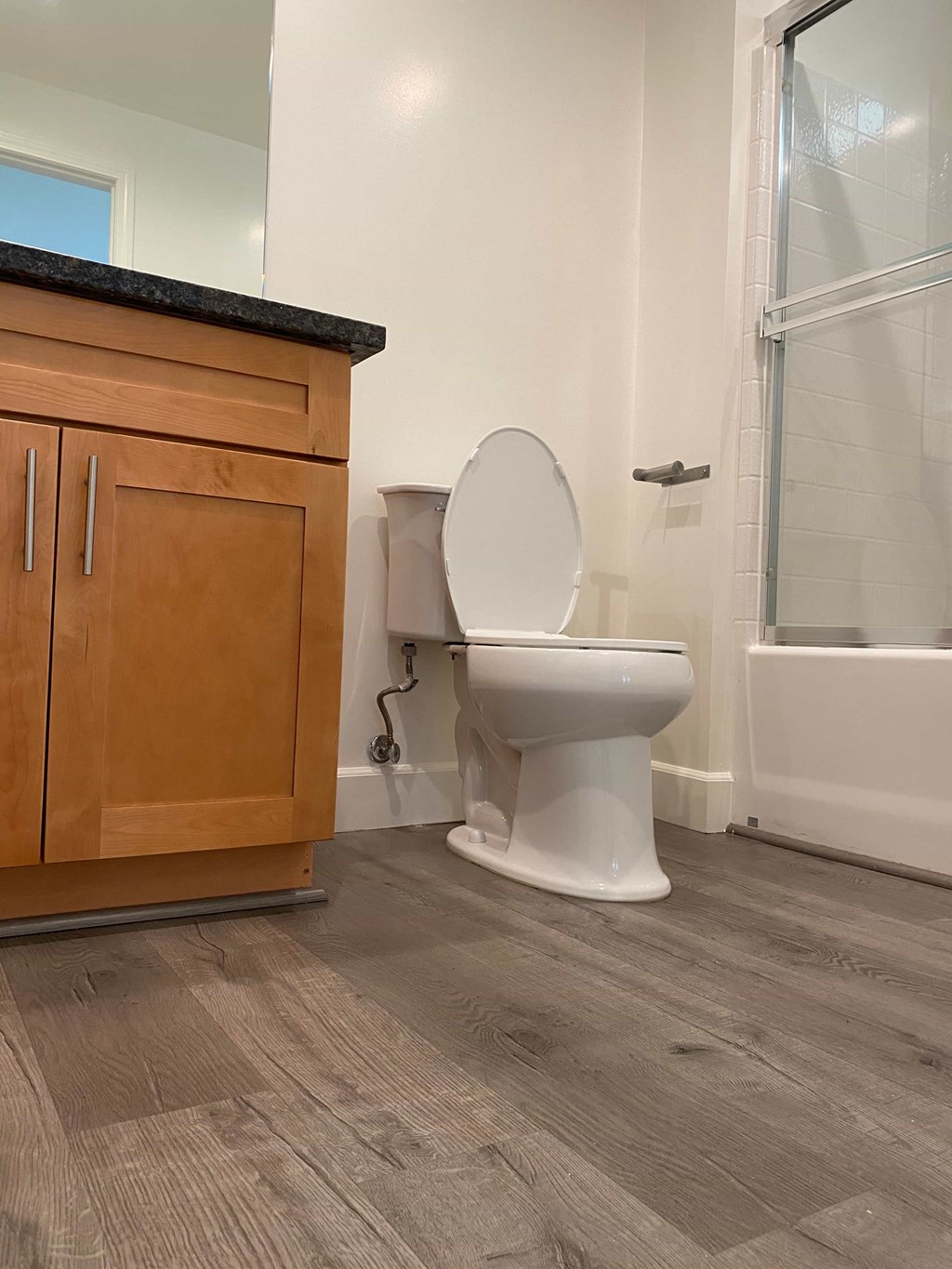A white toilet sits in a bathroom next to a wooden cabinet.