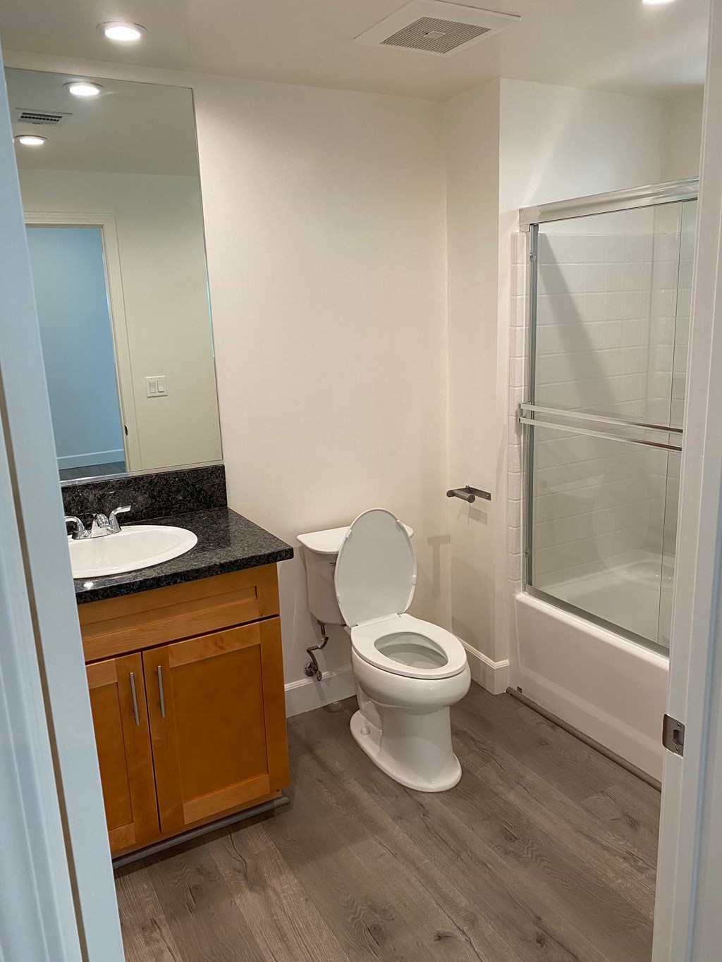A white toilet sits in a bathroom next to a sink and a shower.