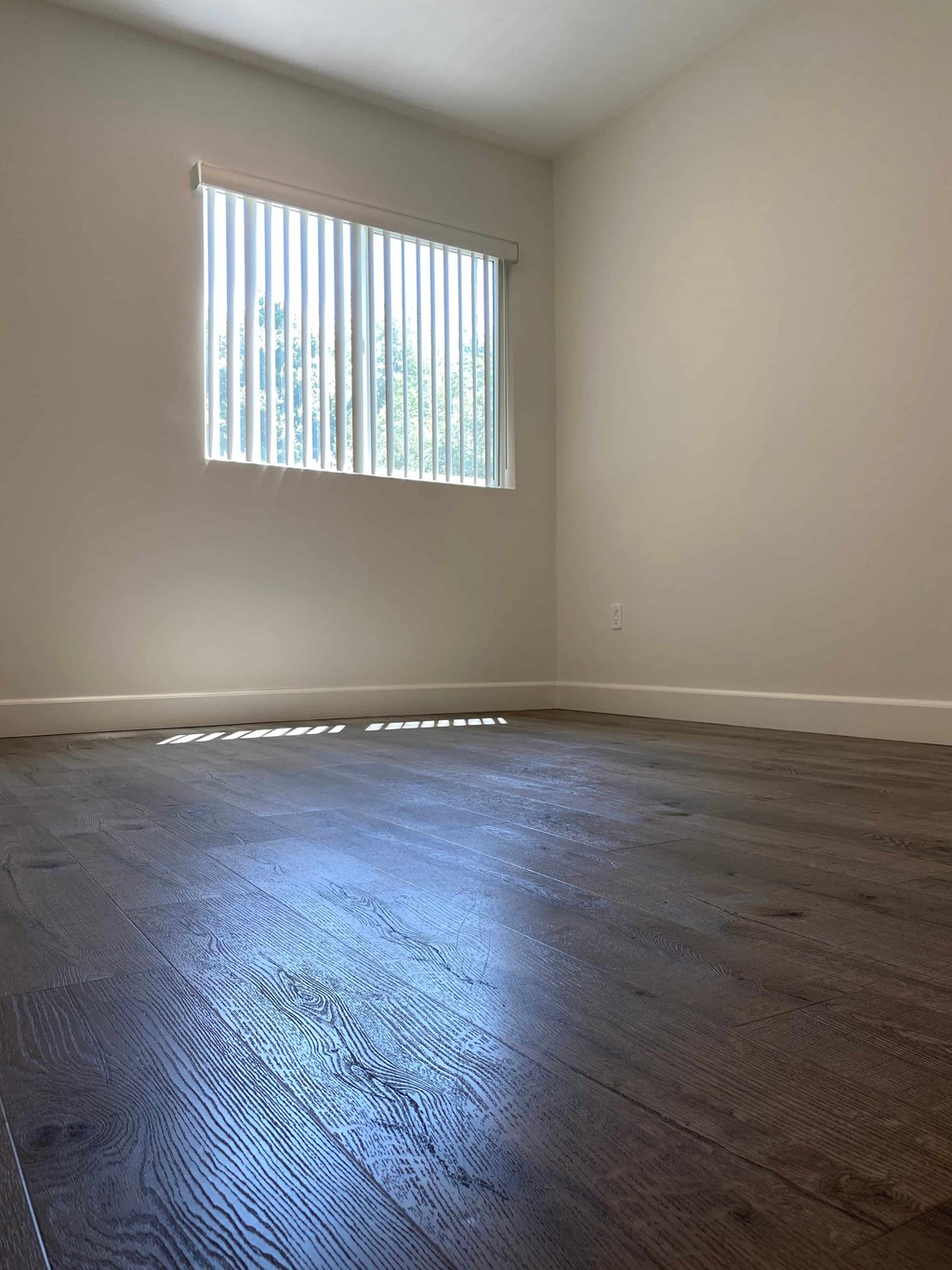 A room with a window and wooden flooring.