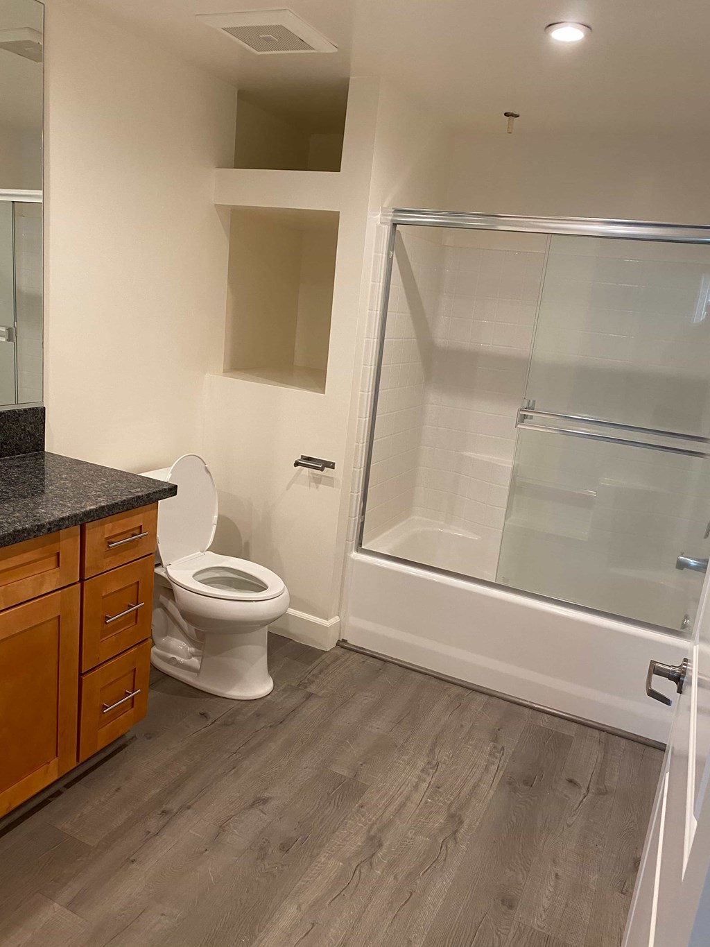 A white toilet sits in a bathroom with a walk-in shower.