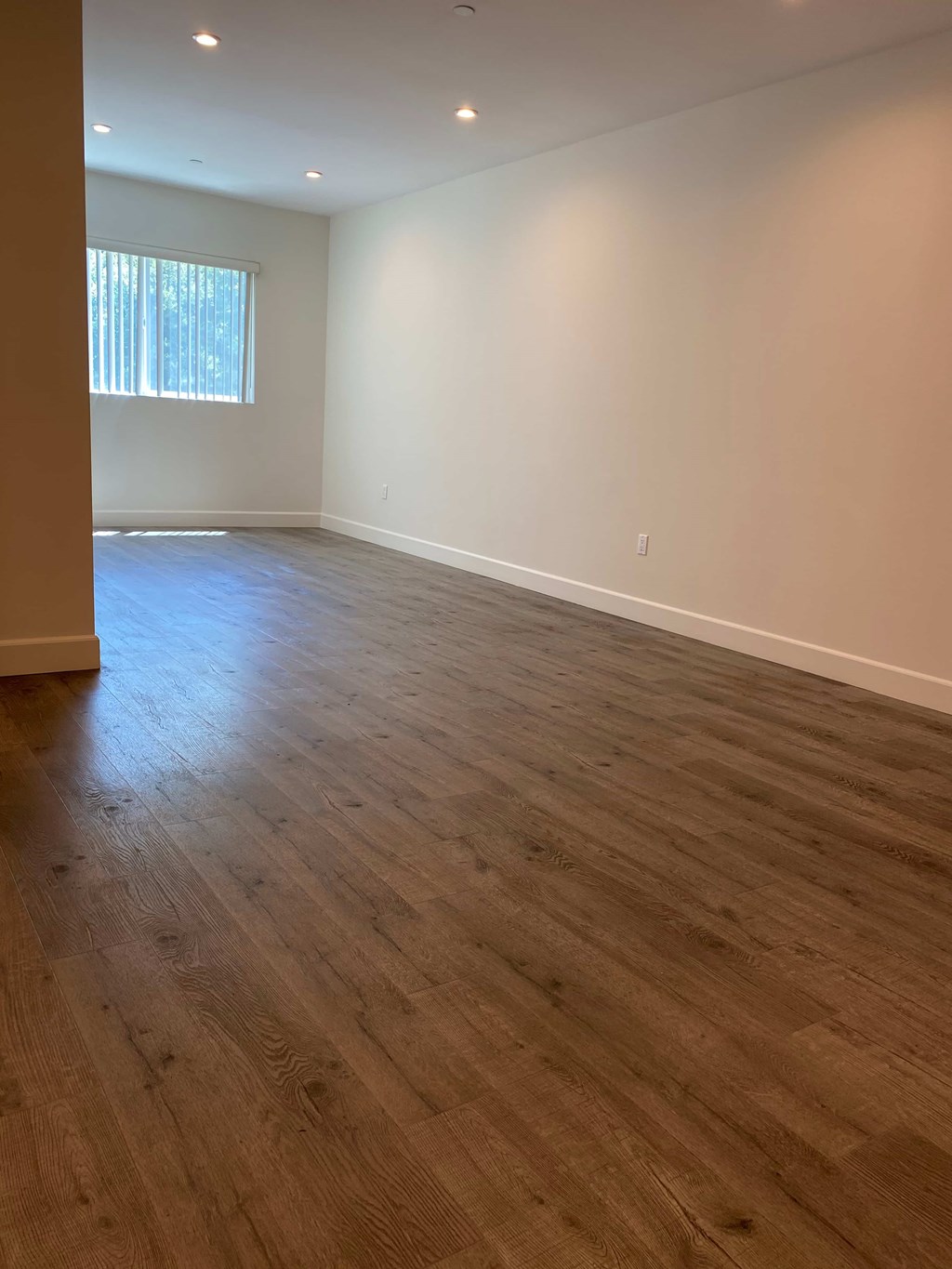 A room with wooden flooring and a window letting in light.