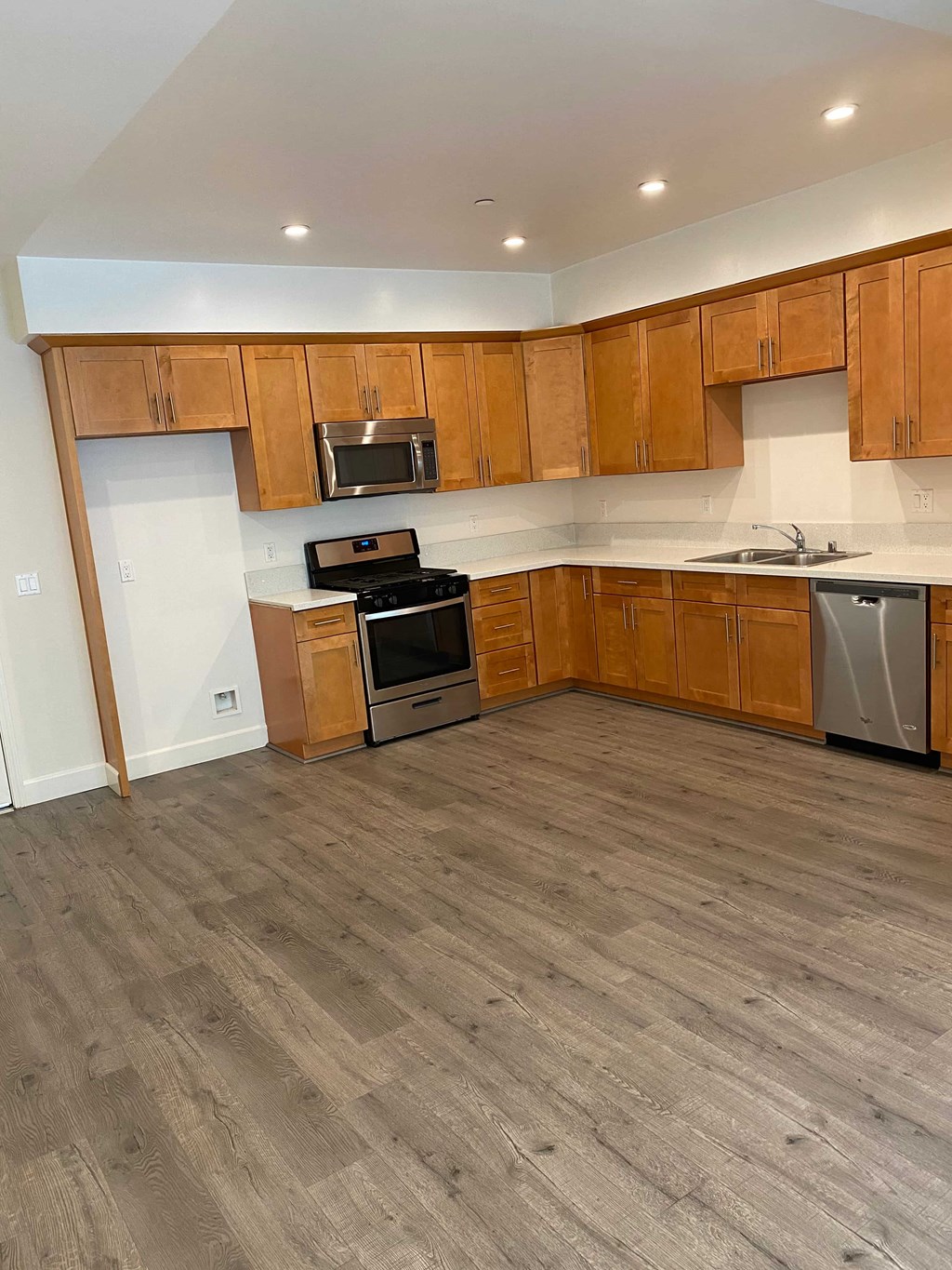 A kitchen with wooden cabinets and a grey floor.