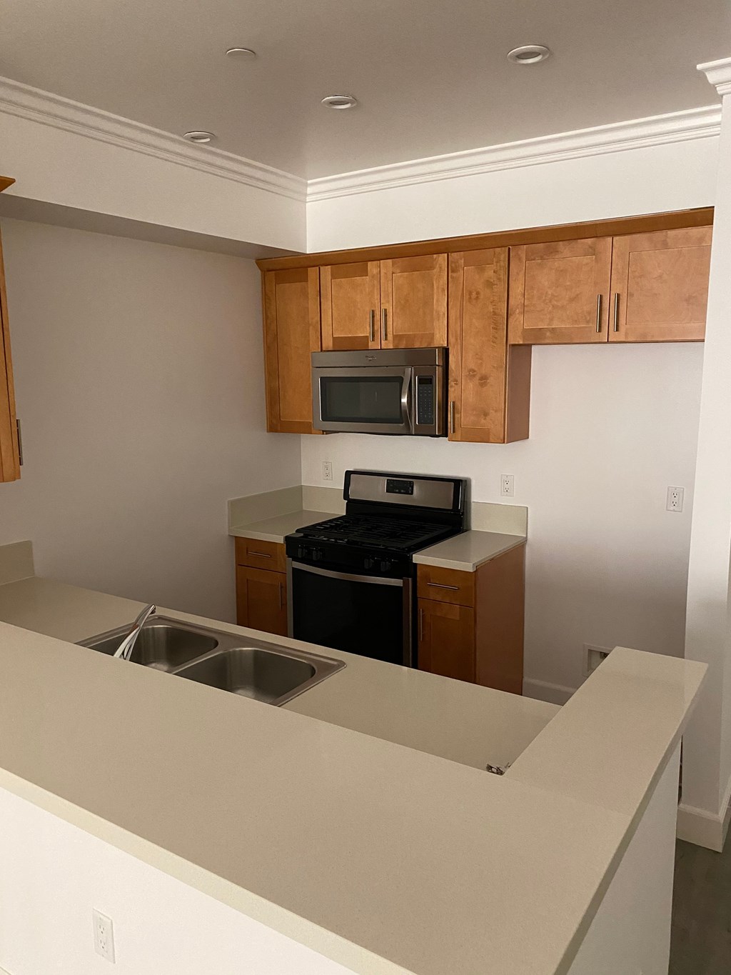 A kitchen with a sink, stove, and microwave.
