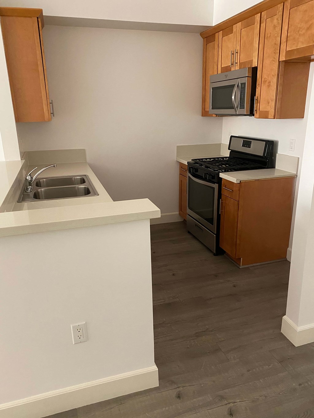 A kitchen with a white counter top and brown cabinets.