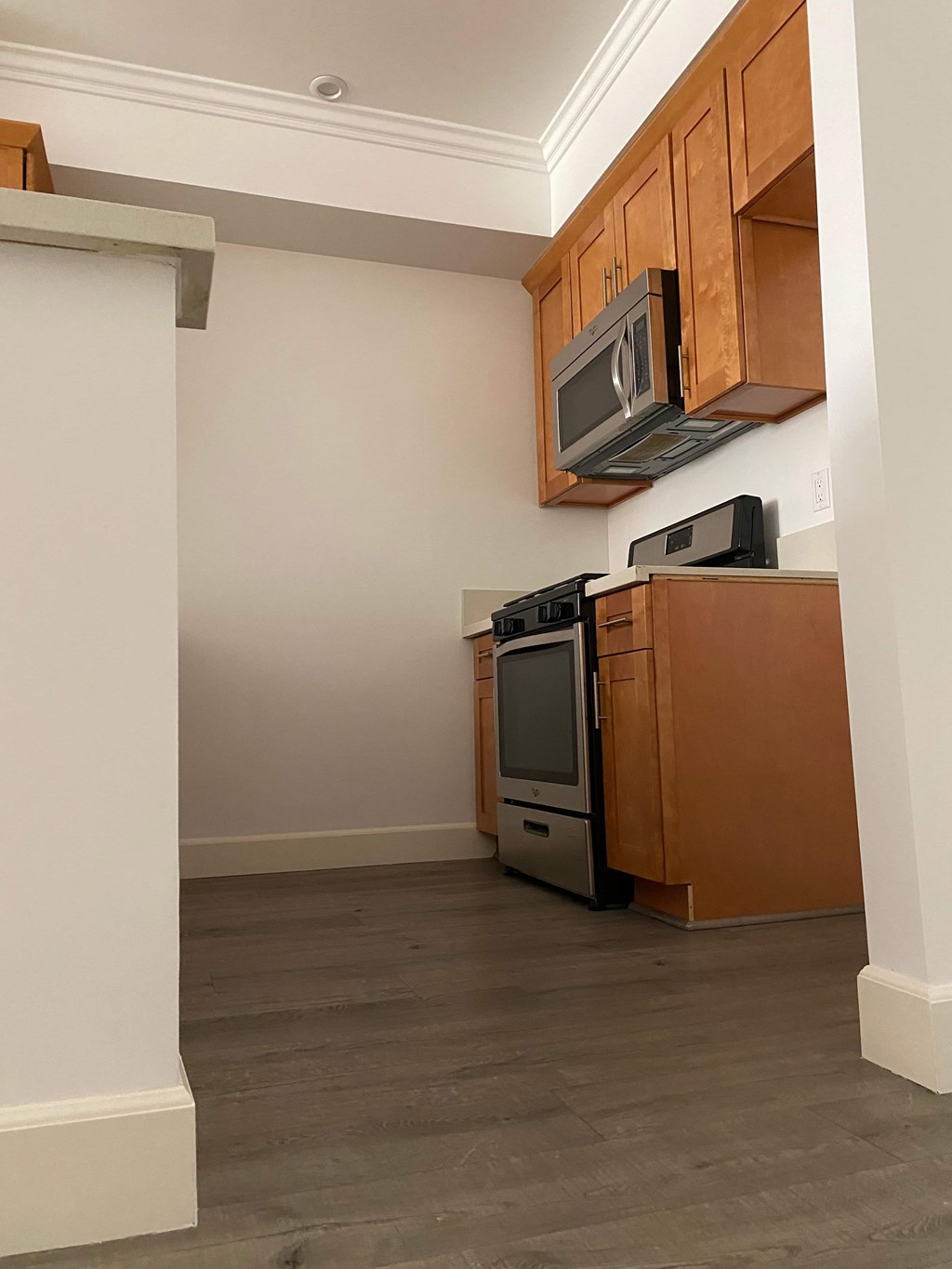 A kitchen with wooden cabinets and a microwave above the stove.