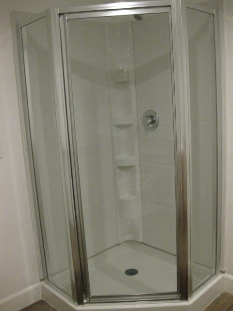 A shower with a glass door and a drain in the bottom.