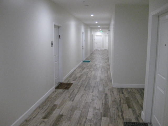 A long hallway with wood flooring and white walls.