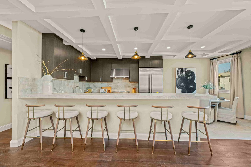 a large kitchen with bar stools in front of a marble counter top