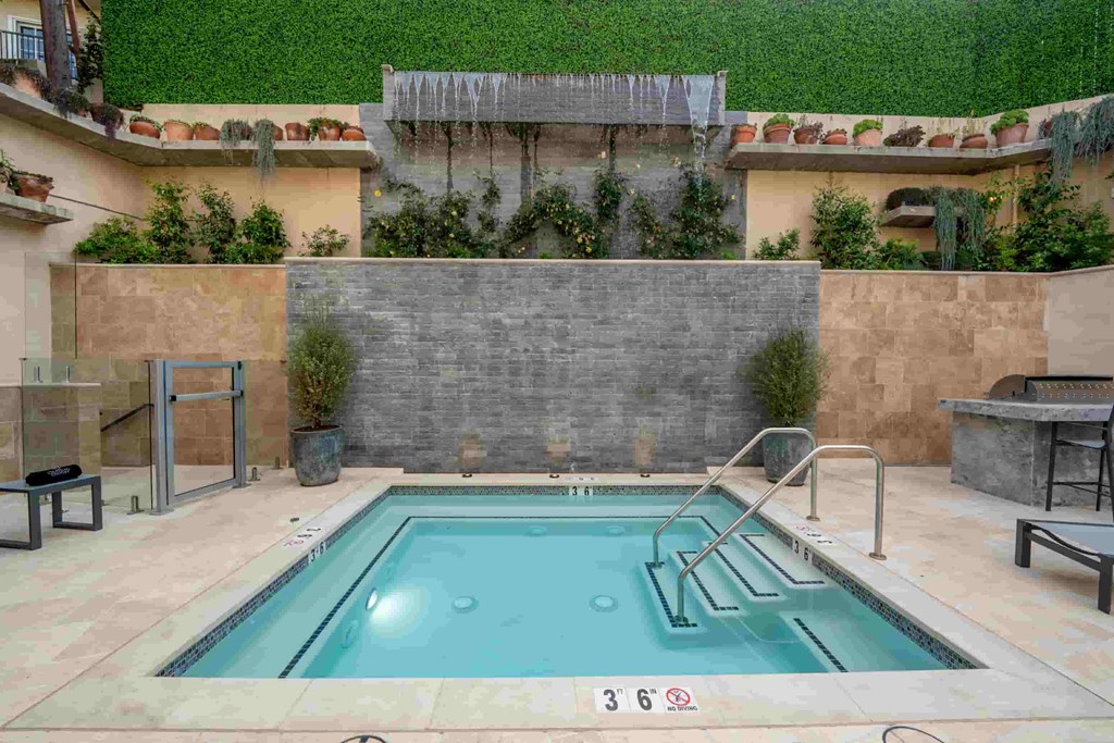the pool is next to a stone wall and a swimming pool