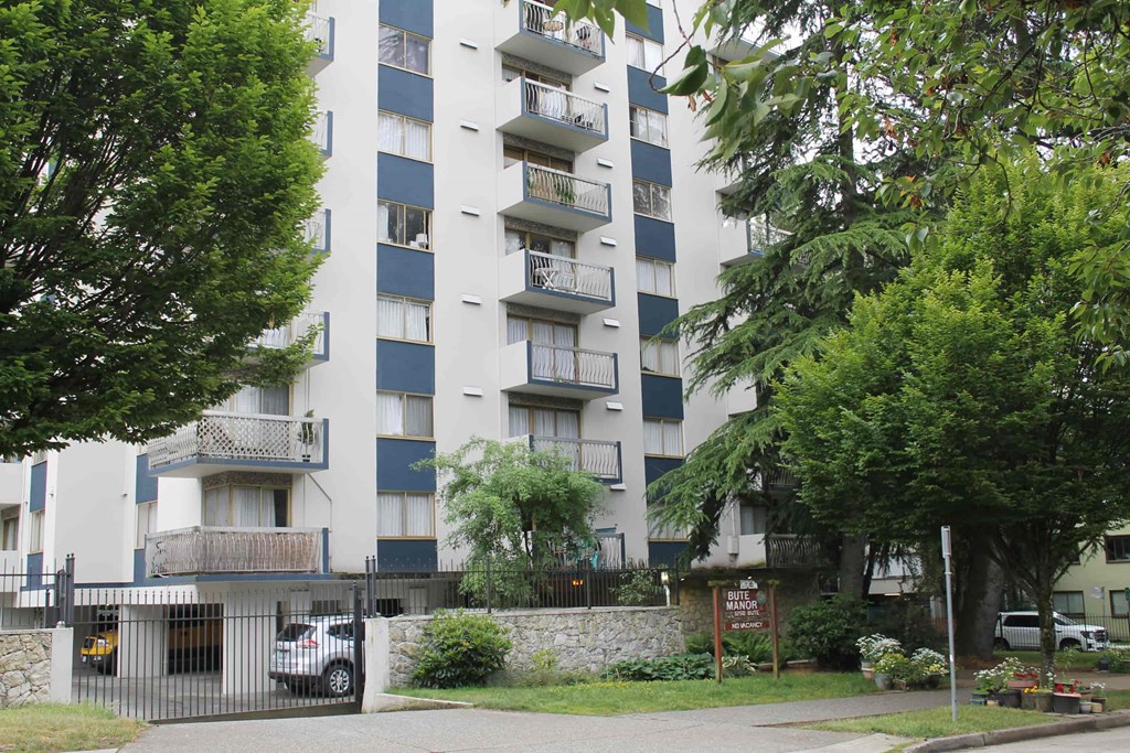 A tall apartment building with balconies and a gate in front.