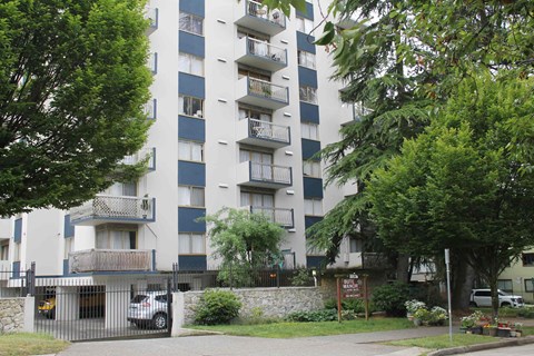 A tall apartment building with balconies and a gate in front.