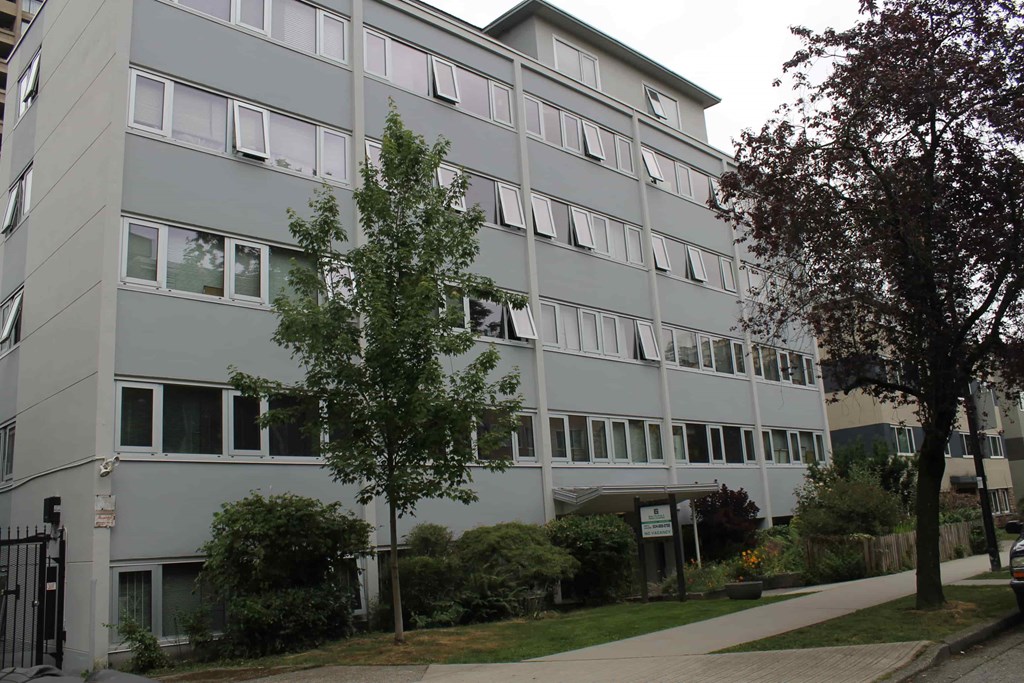 A grey building with a tree in front of it.