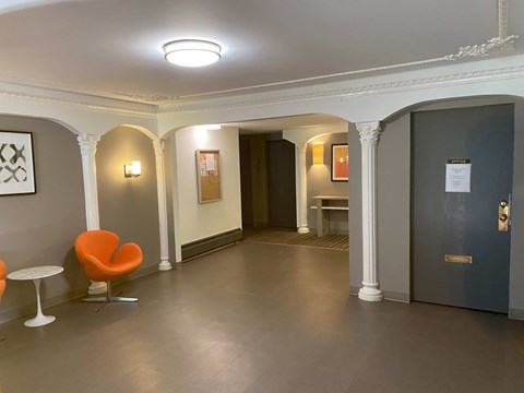 A hallway with a blue door and a red chair.
