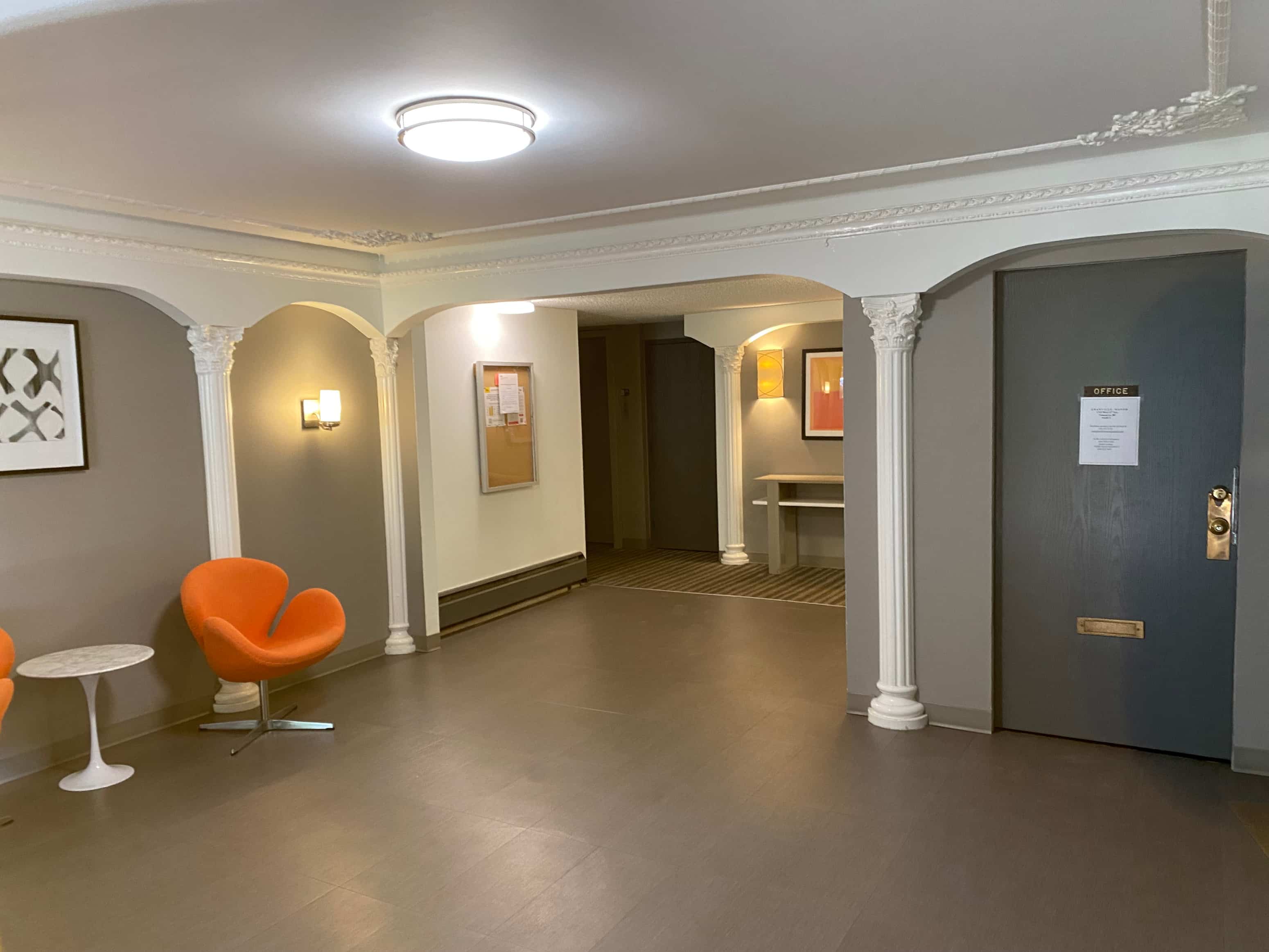 A hallway with a blue door and a red chair.