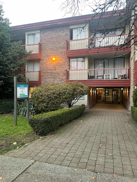 The image shows a red brick building with a signboard in front of it.