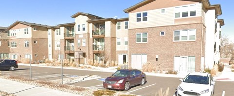 an apartment building with cars parked in a parking lot