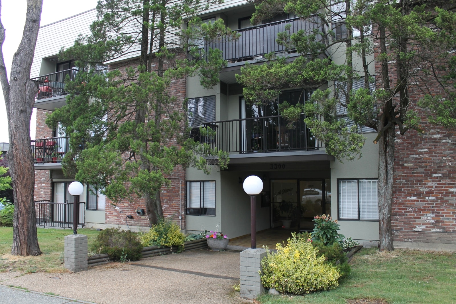 A building with a balcony and a small garden in front.