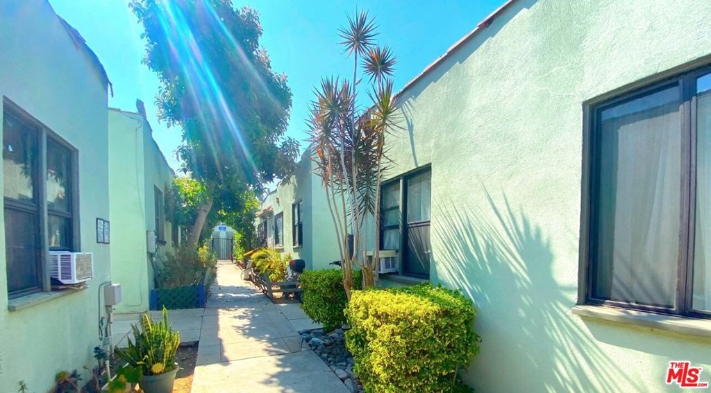 a row of houses with a sidewalk and plants in front of them