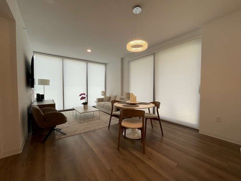 A modern living room with a wooden floor and a dining table set up.