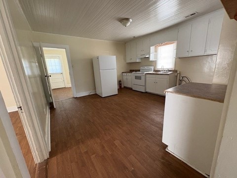 A kitchen with white cabinets and a wooden floor.