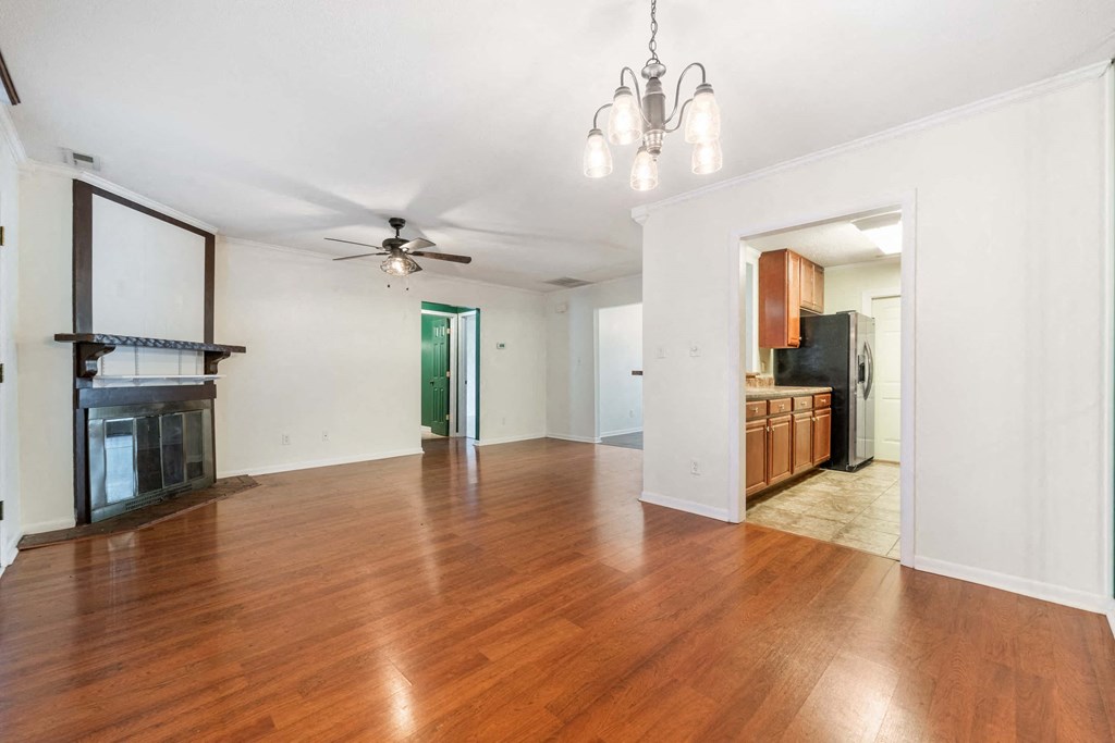 an empty living room and kitchen with wood floors and a ceiling fan