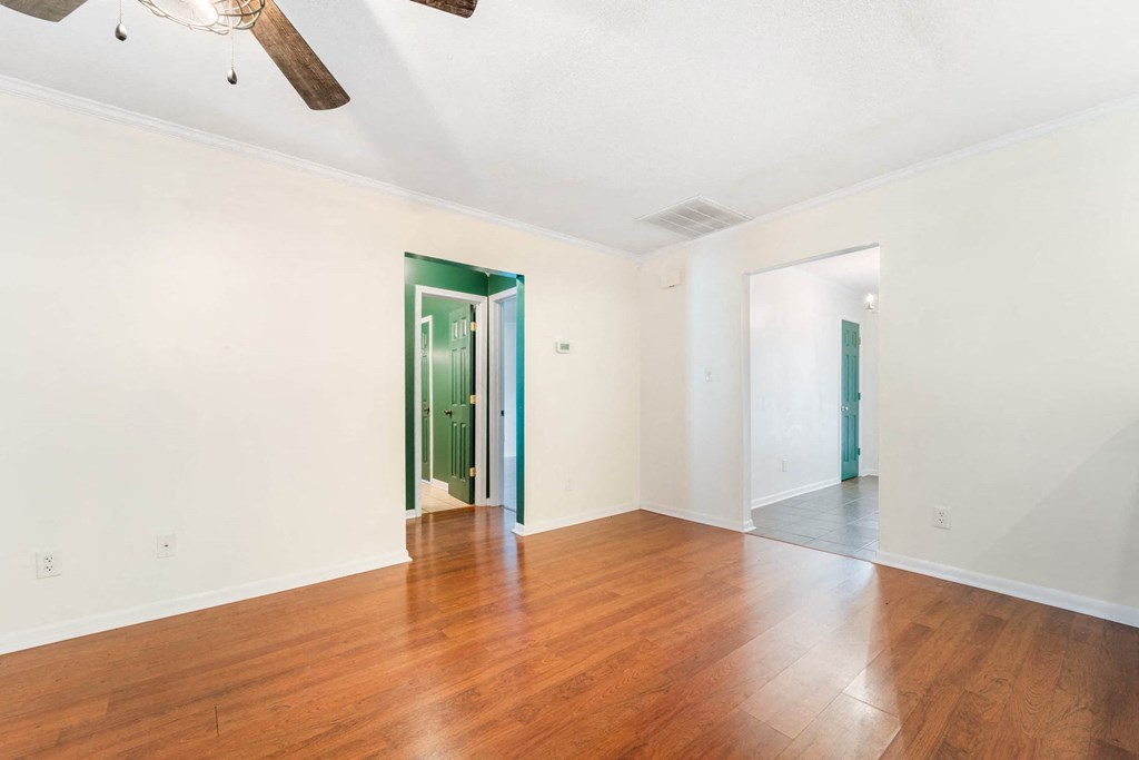 a living room with wood floors and white walls and a green door