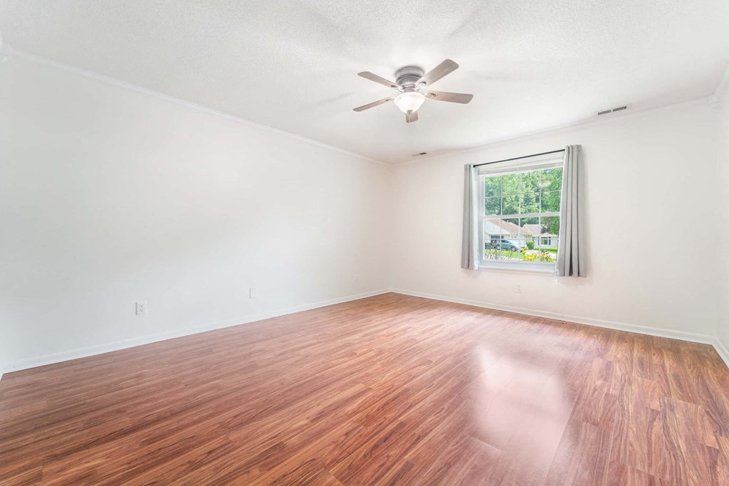 an empty living room with wood floors and a ceiling fan