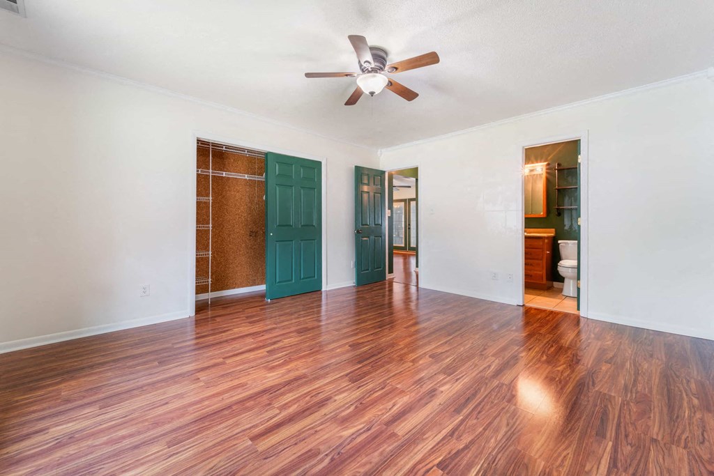 an empty living room with a ceiling fan and a green door