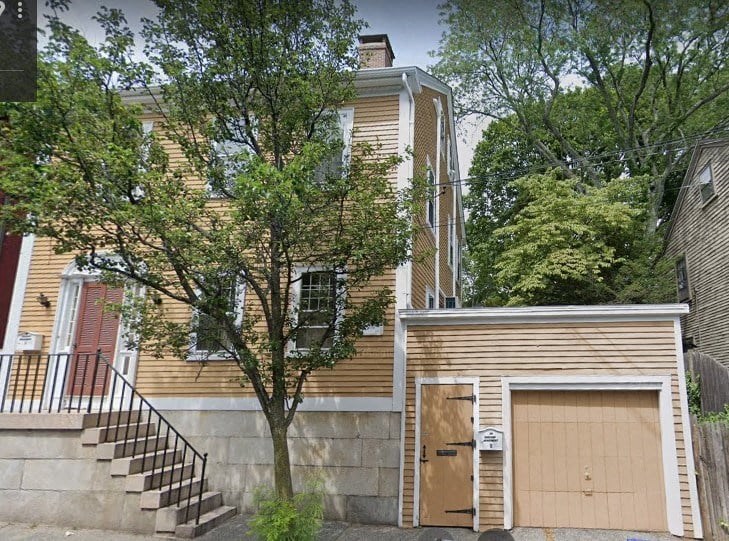 a house with a garage door and a tree in front of it