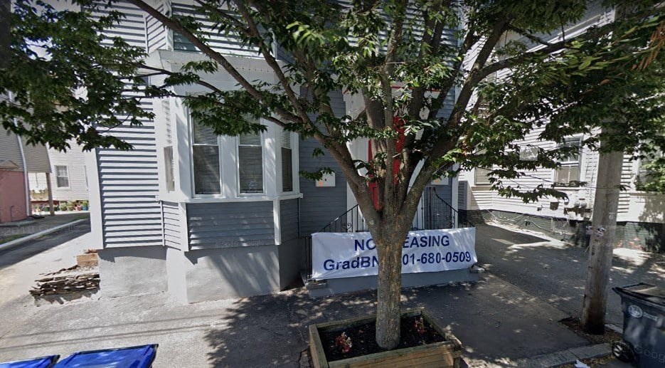 a house with a sign in front of a tree