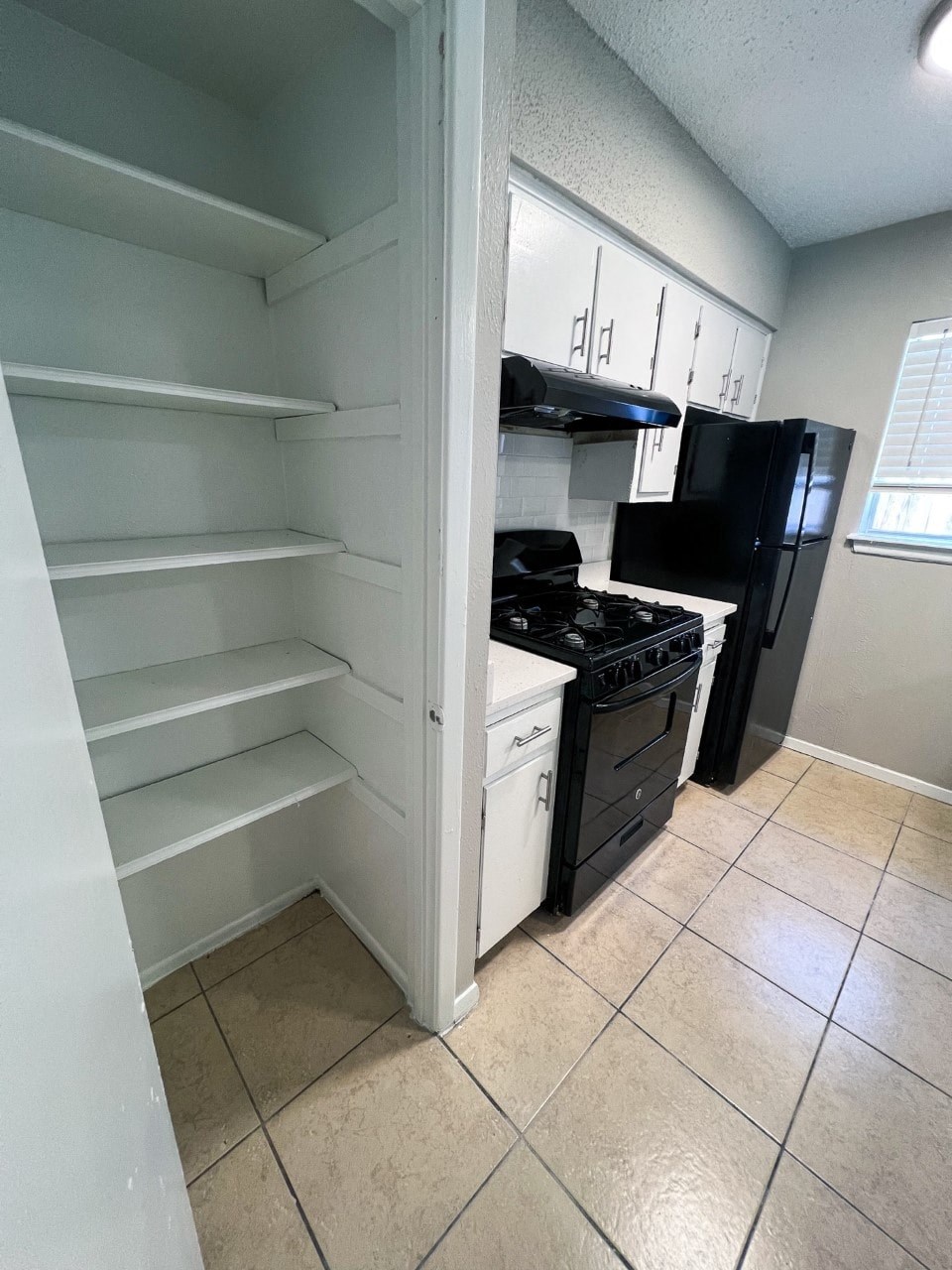 a kitchen with white cabinets and black appliances