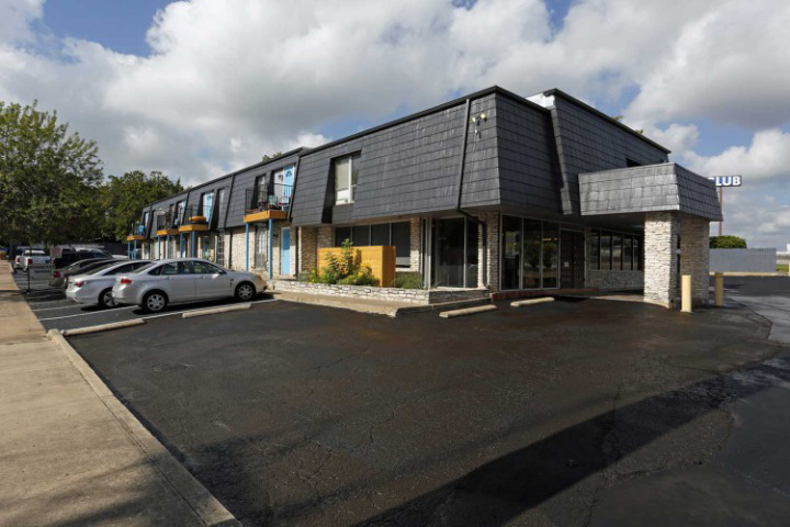 a building with a black roof and a parking lot in front of it