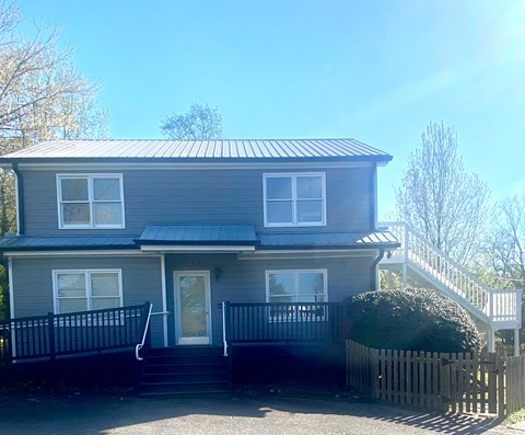 A grey house with a black fence and a white door.