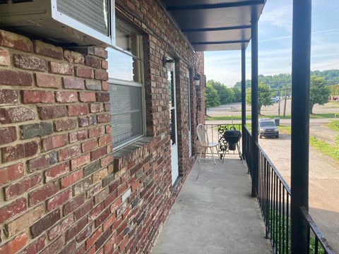 A patio with a black railing and a brick wall.