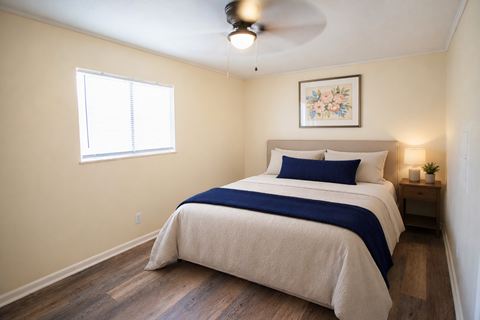 A bedroom with a bed, a ceiling fan, and a small nightstand.
