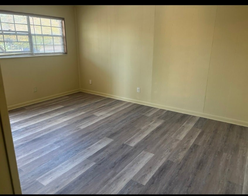 A room with wooden flooring and a window.