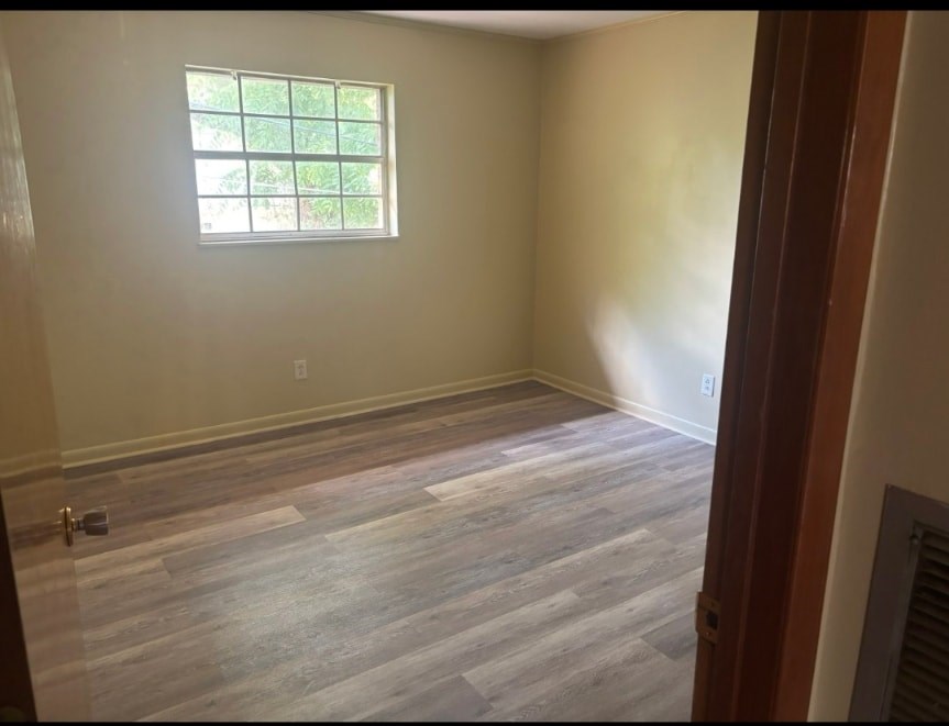 A room with a window and wooden flooring.