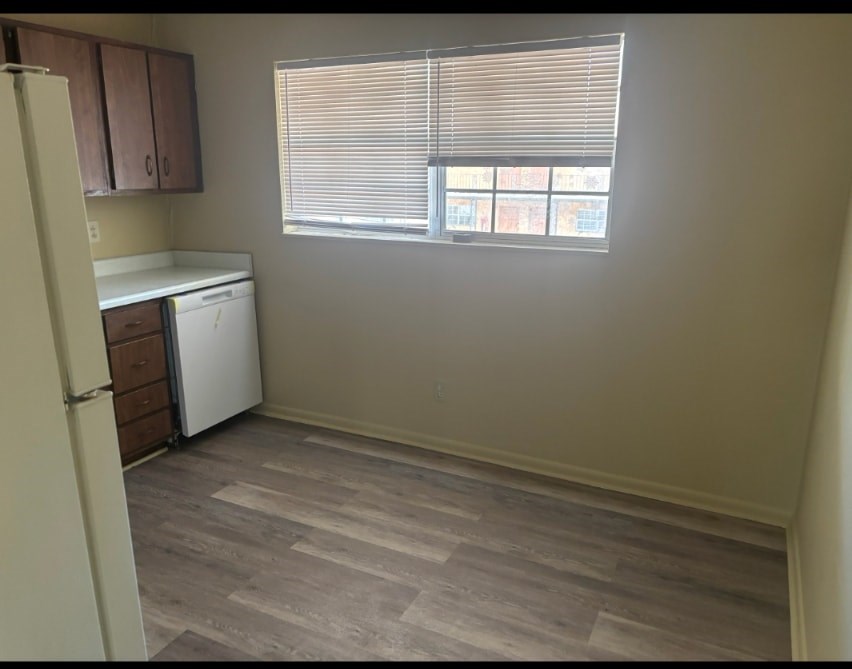 A kitchen with a white refrigerator and a window with blinds.