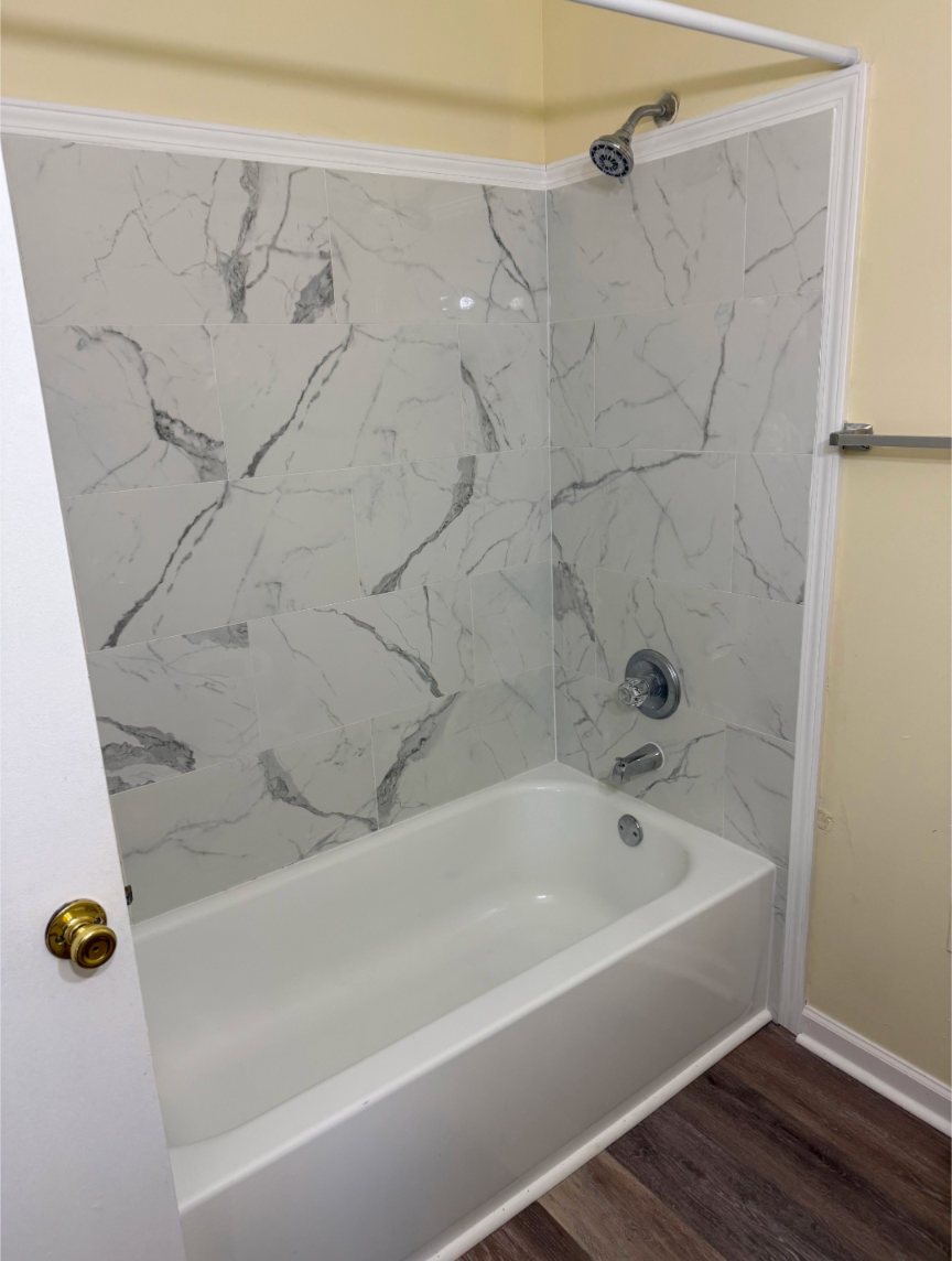 A white bathtub with a marble patterned shower.