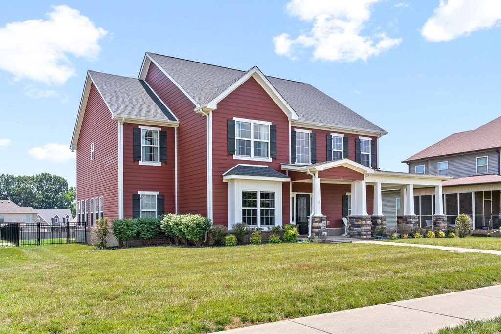 a red house with a yard and a sidewalk in front of it