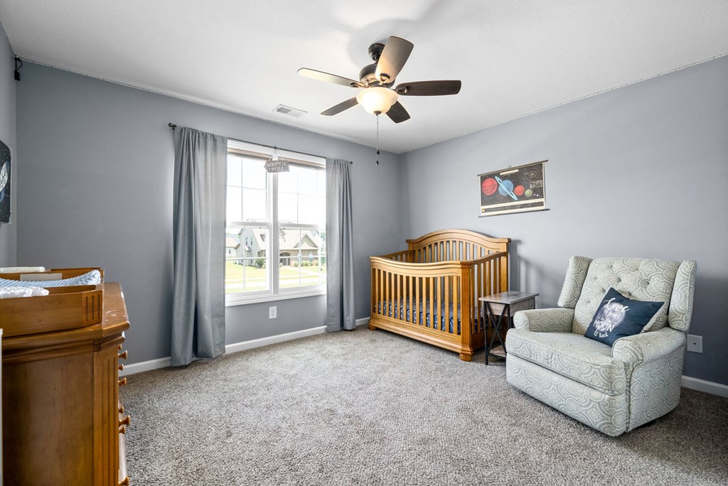 a living room with a baby crib and a ceiling fan