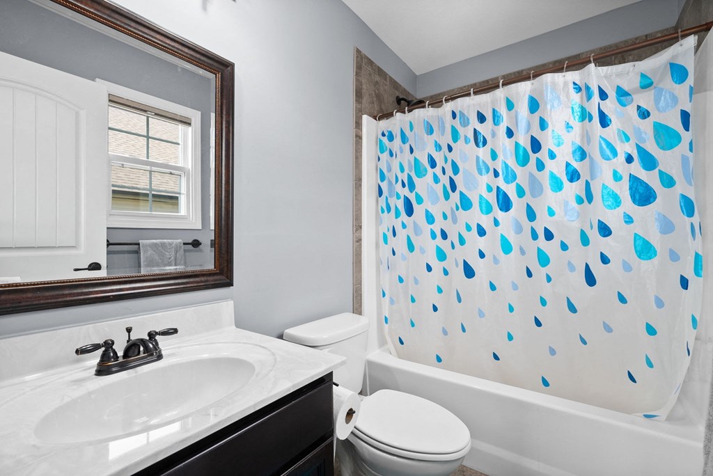 a bathroom with a blue and white shower curtain and a toilet and sink