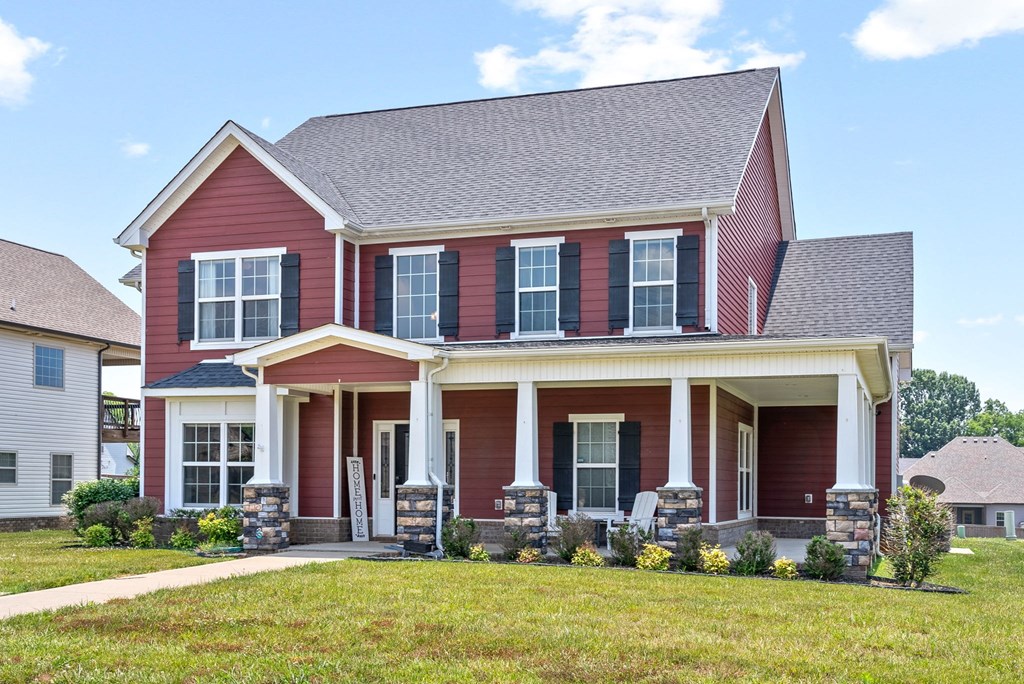 a red house with white pillars and a lawn in front of it