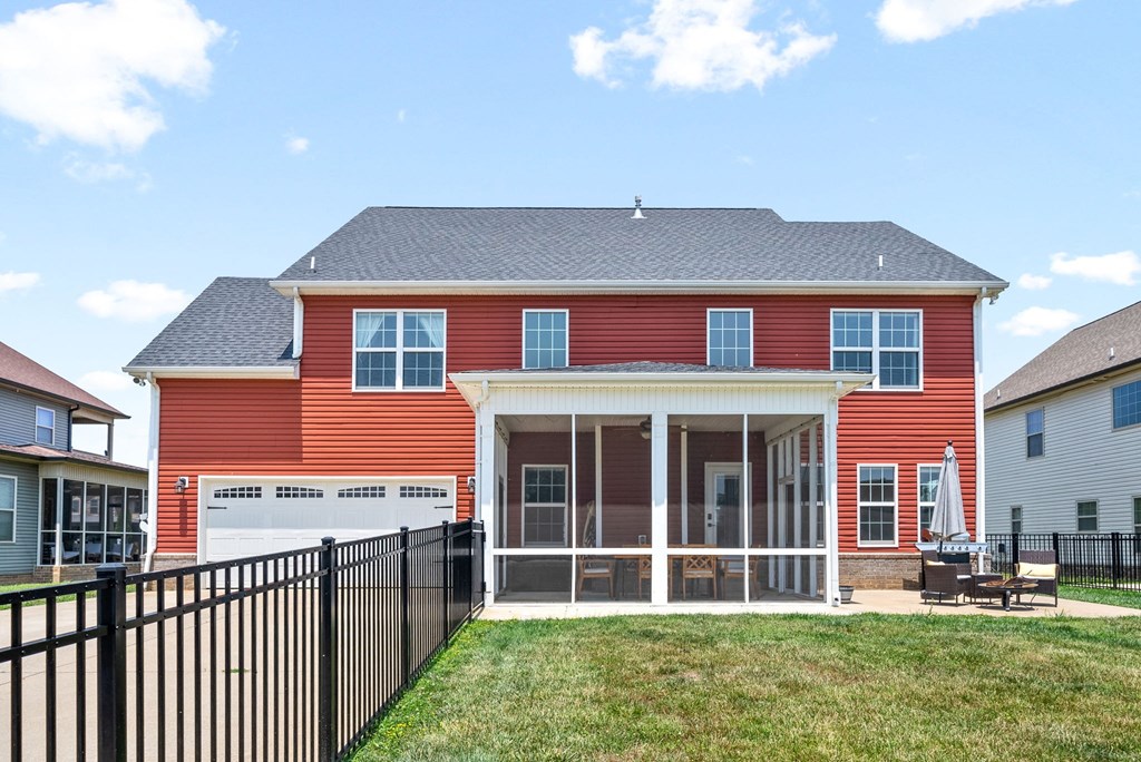 the front of a red house with a yard and a black fence