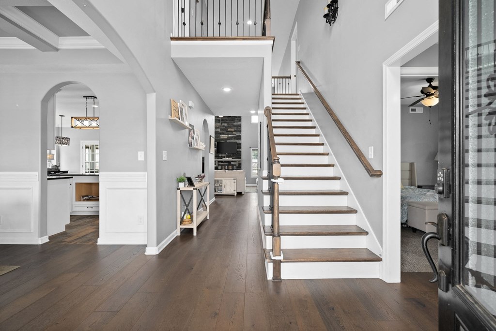 a living room with a staircase and a hallway with a kitchen next to it